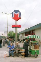 Menschen auf einer Bank beim Eingang zur Metro in Istanbul