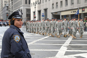 New York City  USA  eine Polizistin am Rande der Parade und marschierende Soldate