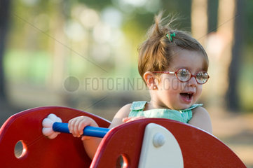 Spanien  kleines Maedchen mit Brille auf einer Wippe