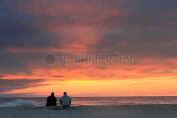 Hvide Sande  Daenemark  Menschen beobachten den Sonnenuntergang am Meer