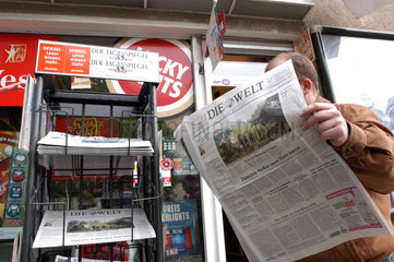 Mann liest die Tageszeitung Die Welt an einem Kiosk