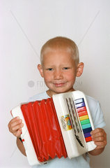 fuenfjaehriger Junge spielt auf seiner Ziehharmonika
