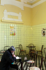 Budapest  Ungarn  ein alter Mann sitzt in einem leeren Cafe und liest mit Lupe