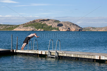 Hamburgsund  Schweden  ein Mann springt von einem Badesteg ins Wasser