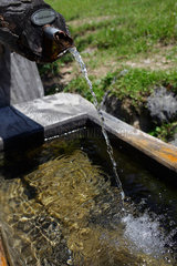 Filzmoos  Oesterreich  Trinkwasser fliesst aus einem Rohr in die Traenke