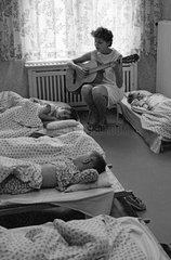 Berlin  DDR  Kindergaertnerin spielt vor dem Mittagsschlaf der Kinder auf der Gitarre