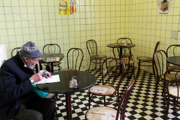 Budapest  Ungarn  ein alter Mann sitzt in einem leeren Cafe und liest mit Lupe