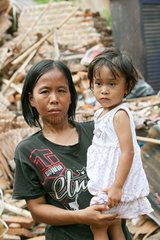 Sungai Rambai  Indonesien  eine Frau mit ihrer Tochter vor einem zerstoerten Haus