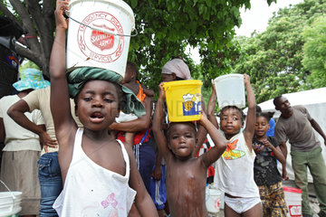 Port-au-Prince  Haiti  Kinder tragen gefuellte Wassereimer auf ihren Koepfen