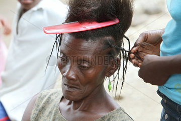 Leogane  Haiti  einer Frau werden Zoepfe geflochten in einem Fluechtlingslager