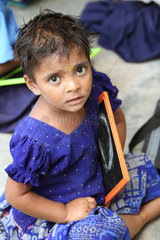 Vijayawada  Indien  eine kleine Schuelerin mit Tafel unter dem Arm beim Unterricht