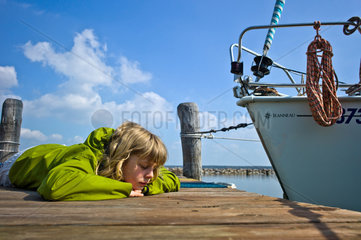 Klink  Deutschland  ein Maedchen liegt auf einem Bootssteg an der Mueritz
