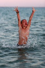 Santa Margherita di Pula  Italien  Junge springt jubelnd aus dem Meer heraus