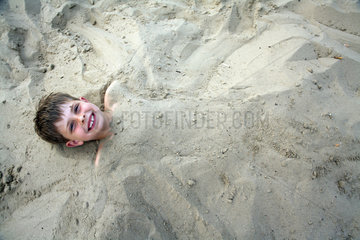 Berlin  Deutschland  ein Junge ist im Sand eingegraben