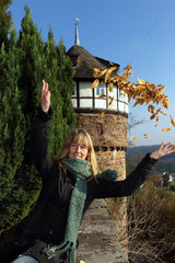 Trendelburg  Deutschland  Frau wirft Herbstlaub vor der Burg Trendelburg in die Luft