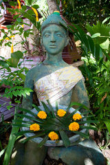Phuket  Thailand  eine Skulptur traegt eine Schale mit gelben Blueten