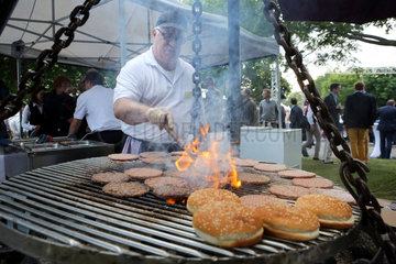 Hannover  Deutschland  Mann bereitet Hamburger auf einem Grill zu