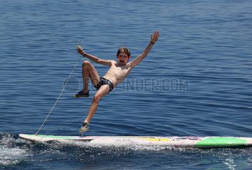 Alicudi  Italien  ein Junge faellt von seinem Surfbrett ins Wasser