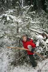 Belloe  Schweden  Junge steht unter einem schneebedeckten Tannenbaum