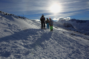 Obertraun  Frau und Kinder laufen an einem Berghang durch den Schnee