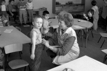 Berlin  DDR  Erzieherin in einem Kindergarten richtet einem kleinen Jungen die Kleidung