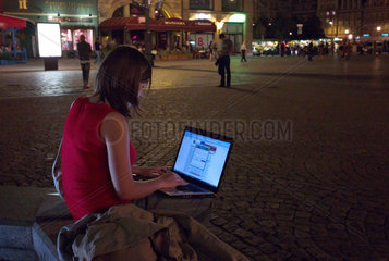 Breslau  Polen  junge Frau chattet am Abend auf dem Marktplatz
