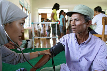 Kampuang Bukik catiak Tawang  Indonesien  Mitarbeiterin der IBU misst bei einem Mann Blutdruck