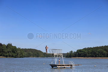 Templin  Deutschland  Mann steht in einem See auf einem Sprungbrett