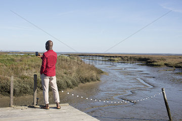 Man standing on dock  looking at multimedia smartphone
