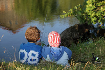 Prangendorf  Deutschland  Kinder sitzen beim Angeln an einem Teich