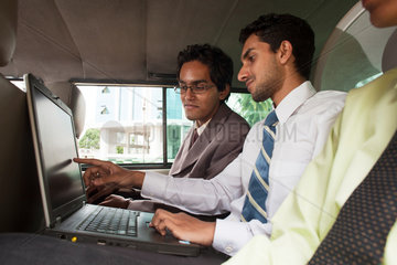 Coimbatore  Indien  junge indische Geschaeftsmaenner mit Laptop in einem Auto