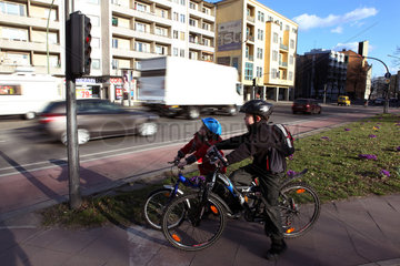 Berlin  Deutschland  Kinder warten auf ihren Fahrraedern an einer roten Fahrradampel