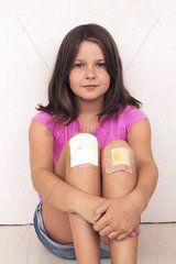 Girl hugging bandaged knees  portrait
