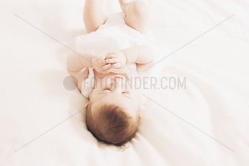 Baby lying on bed playing