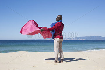 Man at the beach  holding blanket in the breeze