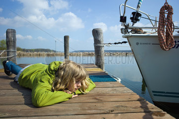 Klink  Deutschland  ein Maedchen liegt auf einem Bootssteg an der Mueritz