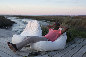 Man relaxing on dock at water's edge