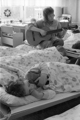 Berlin  DDR  Kindergaertnerin spielt vor dem Mittagsschlaf der Kinder auf der Gitarre
