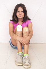 Girl hugging bandaged knees  portrait