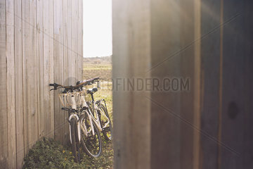 Pair of bicycles leaning against wooden fence