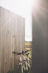 Pair of bicycles leaning against wooden fence