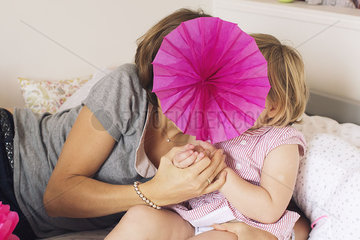 Mother and daughter hiding behind tissue paper flower