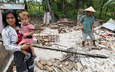 Pariaman  Indonesien  eine Familie vor ihrem zerstoerten Haus im Erdbebengebiet
