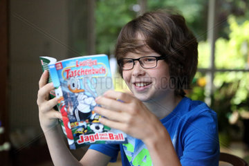 Berlin  Deutschland  Junge mit Brille liest einen Comic
