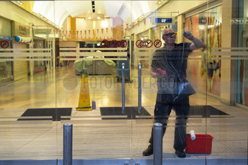Oxford  Grossbritannien  Fensterputzer reinigt die Eingangstuer einer Einkaufspassage
