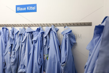 Berlin  Deutschland  Schild Blaue Kittel in einem Umkleideraum bei Freiberger Lebensmittel