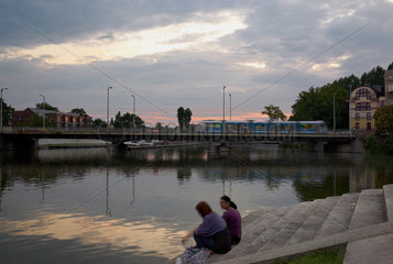 Breslau  Polen  zwei Frauen sitzen in der Abenddaemmerung am Ufer der Oder