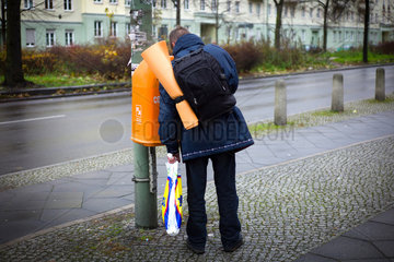 Berlin  Deutschland  Mann sucht in einem Muelleimer nach Flaschen