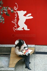 Berlin  Deutschland  eine Frau sitzt auf einer Bank unter dem Berlinale Logo und liest
