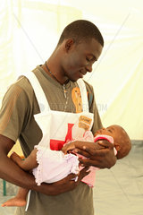 Carrefour  Haiti  ein DRK-Mitarbeiter mit einem kleinen Maedchen im Arm